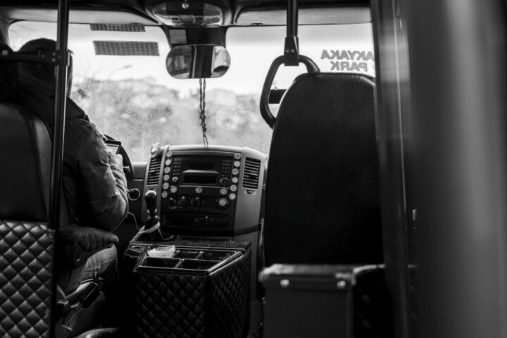 Een buschauffeur in opleiding tijdens een proefrit met een moderne bus, omringd door verkeerssituaties.